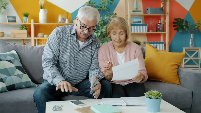 Pareja de adultos mayores revisando documentos de su pensión