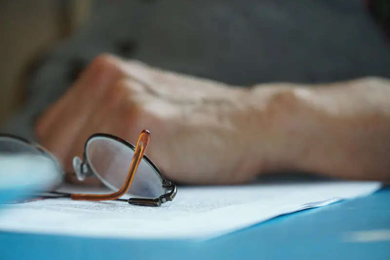 Mano de un adulto mayor con gafas sobre documentos