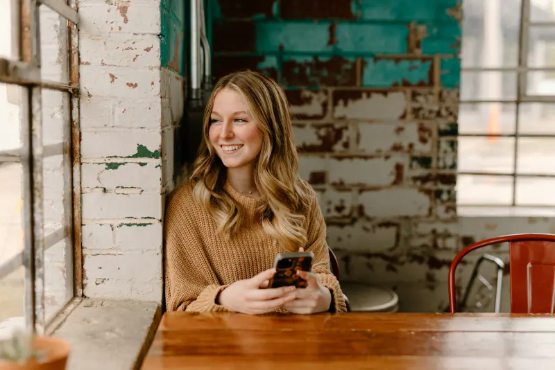 Mujer sonriendo mientras revisa su celular