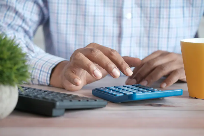 Persona haciendo cuentas con una calculadora sobre un escritorio