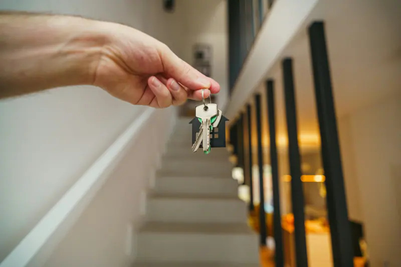 Mano con llaves y un llavero en forma de casa, al calcular cuánto cuesta una sucesión
