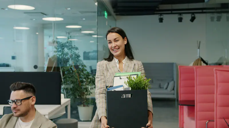 Trabajadora saliendo de la oficina con una caja de pertenencias