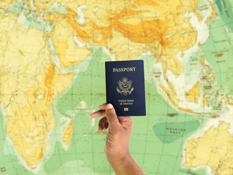 Mano con un pasaporte sobre un mapa para hacer trámites legales en Colombia desde el exterior