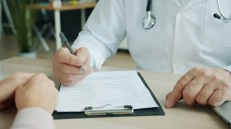 Médico diligenciando la historia clínica y las órdenes de un paciente